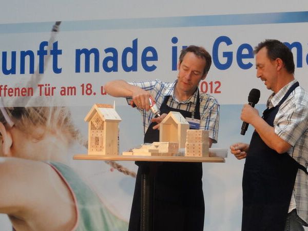 Cornelis Hemmer zeigt auf der Bühne, wie man eine Wildbienen-Nisthilfe zusammenbaut.